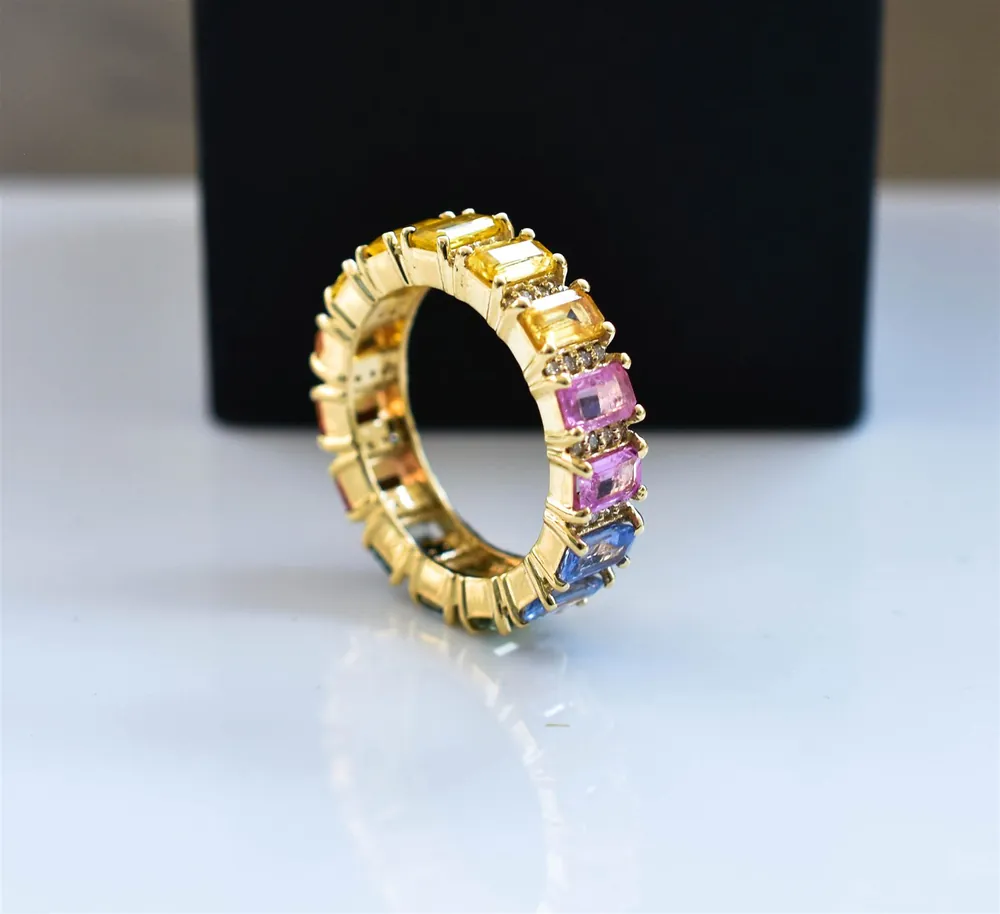 Multicolour gemstone eternity band in gold displayed on a black jewellery box