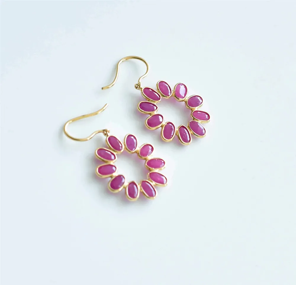 Ruby flower-petal hoop earrings in gold on a pale studio backdrop