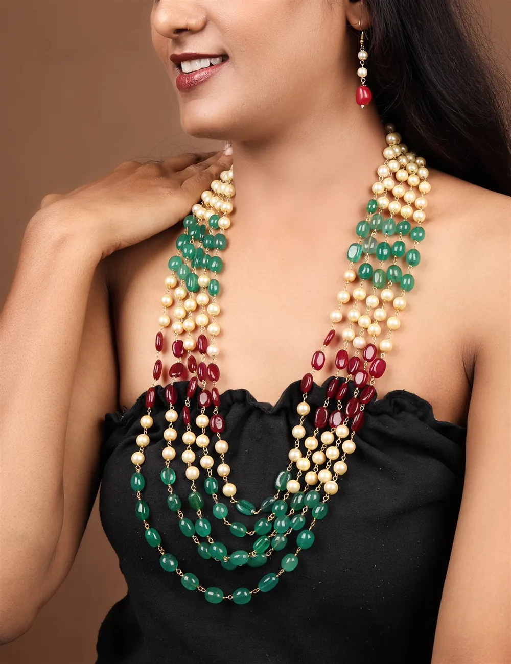 Multi-strand emerald, ruby and pearl necklace worn by a model, studio portrait